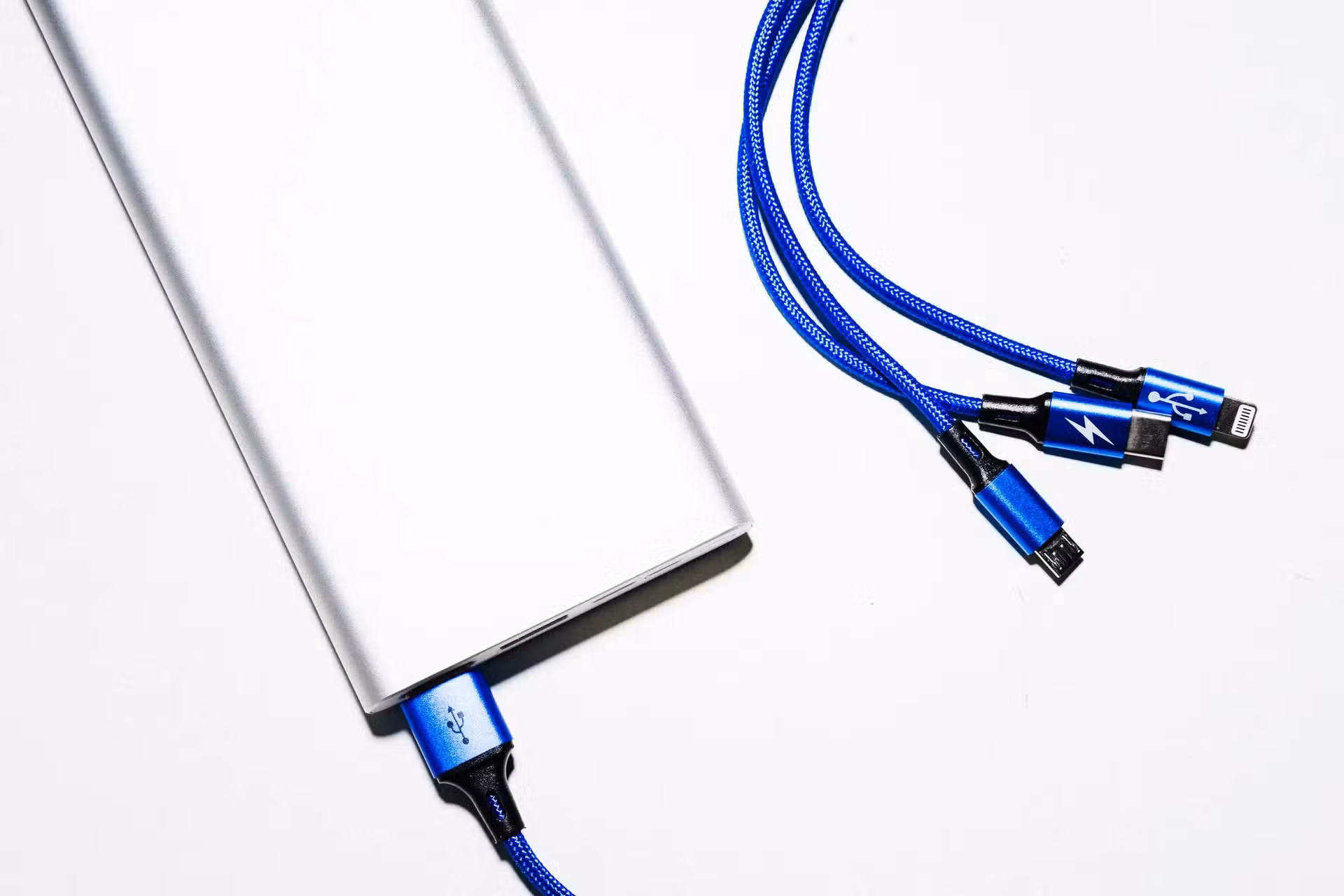 Powerbank i kable USB w oplocie na białym tle